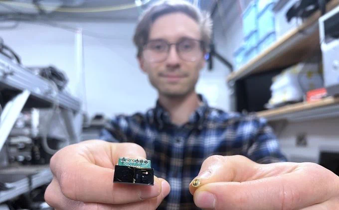 Andrei Isichenko holding up to the camera a ring resonator in his left hand and a Fabry-Perot laser diode in his right hand.