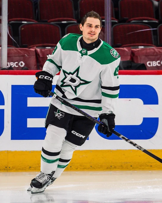 Photo of Justin Hryckowian in a Dallas Stars away uniform skating in warmups without a helmet. 