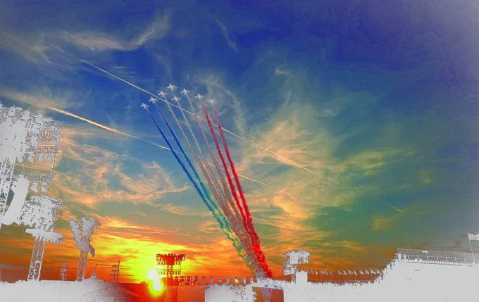 Ocho aviones militares dibujan la bandera francesa con sus estelas de colores. Anochecer en París. A la izquierda hay la silueta de los focos que alumbrarán la inauguración de los Juegos Parilímpicos.