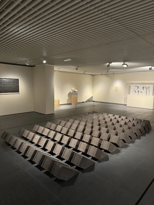 A photograph showing an installation consisting of a large grid of rectangular concrete blocks arranged on a gallery floor.