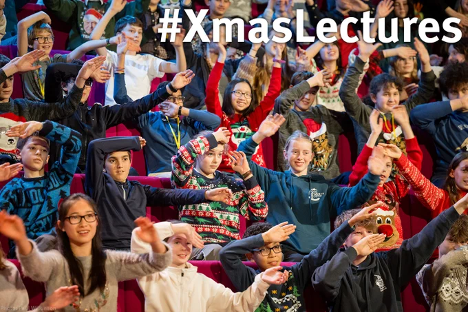 Children in the Christmas Lectures audience wave their arms in the air as part of a demo
