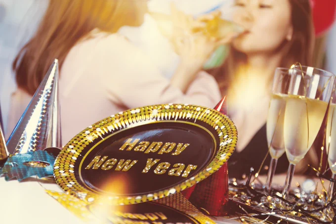 New Year's Eve celebration happening with "Happy New Year" sign in foreground.
