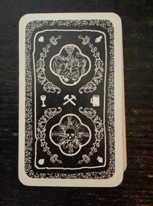 back of playing card with mining tools and skull design