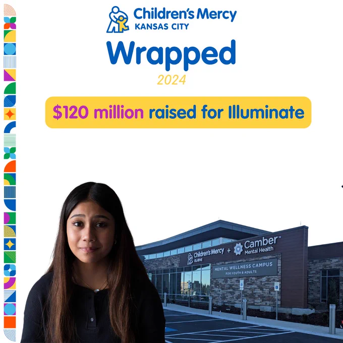 An individual stands in front of a promotional graphic for Children's Mercy Kansas City, highlighting the achievement of raising $120 million for Illuminate in 2024. In the background, the Children's Mercy Kansas City building is visible.