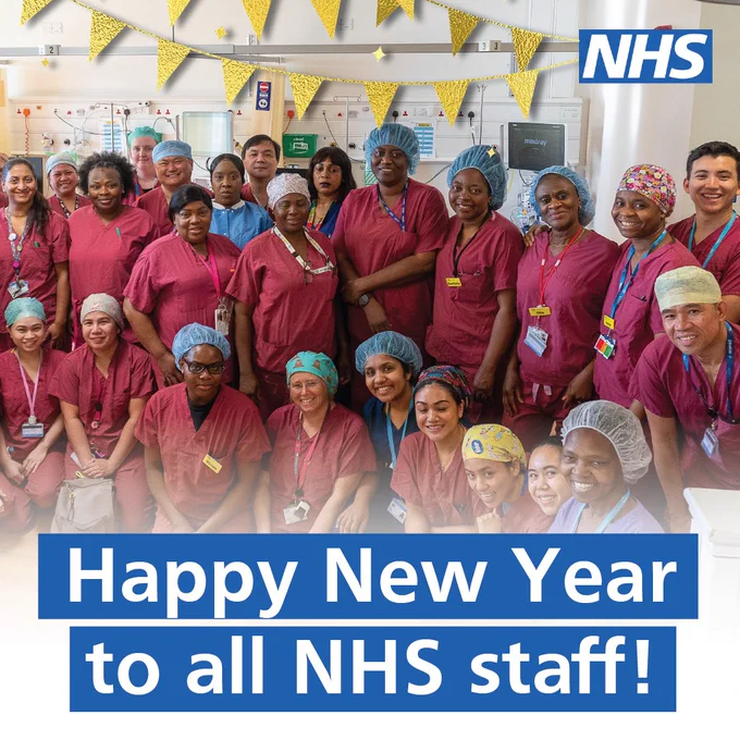 Group photo of diverse NHS staff in scrubs and surgical caps, smiling and standing in a hospital setting decorated with gold banners. Text overlay reads 'Happy New Year to all NHS staff!' with an NHS logo in the top-right corner.