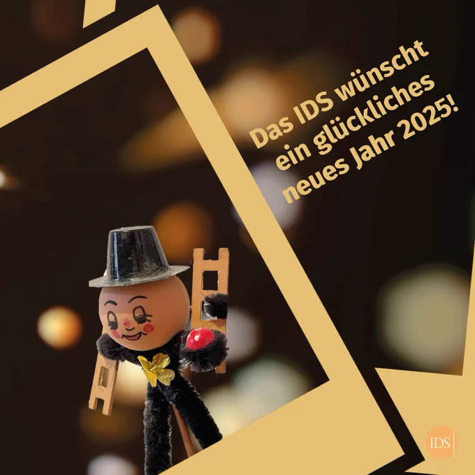 Zu sehen ist eine kleine Schornsteinfeger-Figur mit der nebenstehenden Beschriftung: "Das IDS wünscht ein glückliches neues Jahr 2025!"