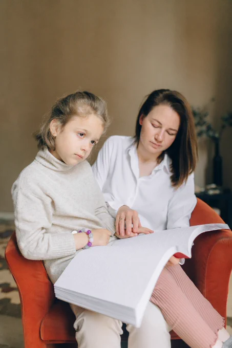 A teacher helping a blind child learn Braille.
