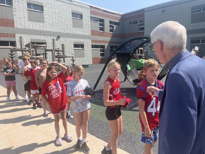 Gov. Evers gives kids "knuckles" and high-fives during recess. 
