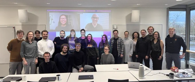 The group standing in front of a meeting room smiling towards the camera.