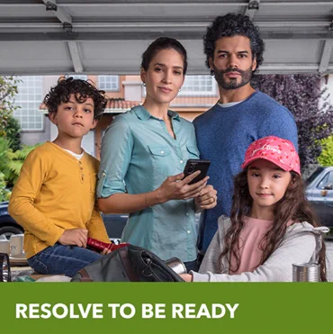 A family gathered in their garage holding some preparedness supplies.