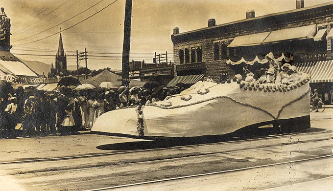 A historical photo of a shoe float going down the street.