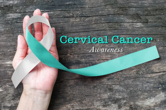 Hand holding a teal colored ribbon with text that reads: Cervical Cancer Awareness.