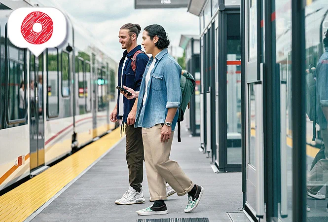 Two students at Carleton Station about to board the train. The Next Stop Blog logo in the top left corner. 