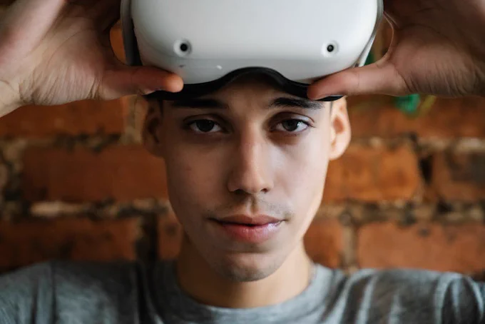 Close-up of a man wearing an AR headset indoors with a brick wall background.