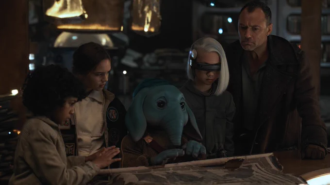 A still from Star Wars: Skeleton Crew featuring our cast of characters investigating a scroll. From left to right: Wim, Fern, Neel, KB, and Jod.