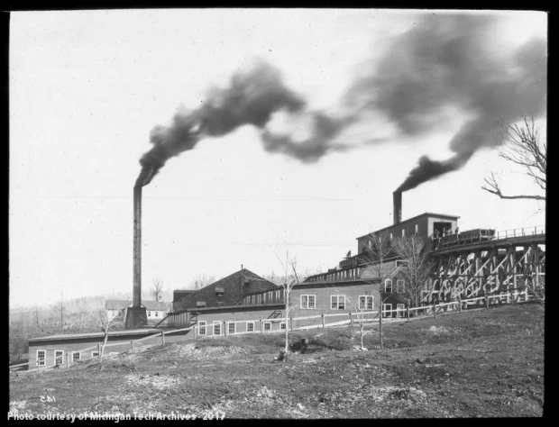 Stamp mill on a hill with smoke pumping from its stacks
