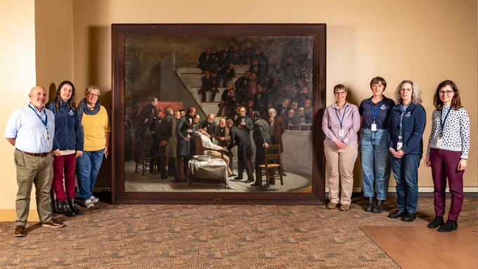Library staff pose with Robert C. Hinckley’s painting The First Operation Under Ether, now uprighted