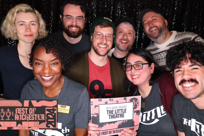 8 people smiling with a sign that says “Best Movie Theater: The Little Theatre”