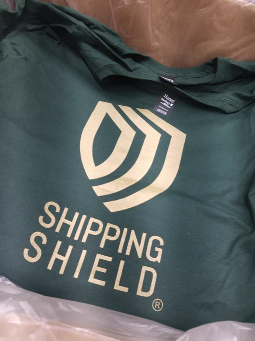 Forest green tee printed with metallic gold shipping shield logo