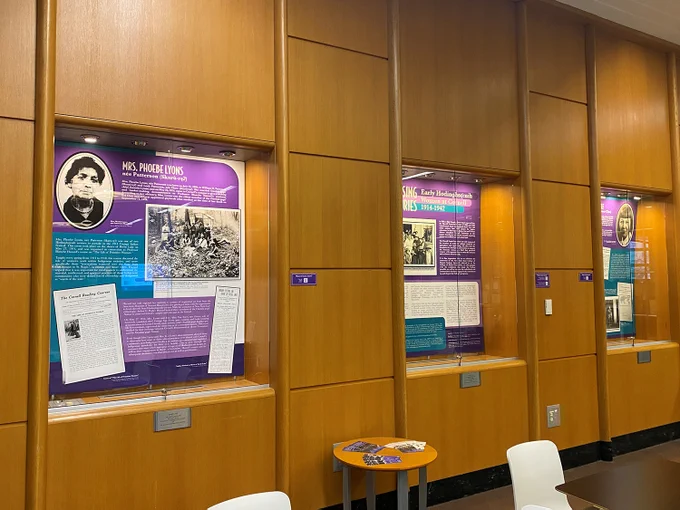 Photo of exhibit cases with panels from an exhibit focused on the history of Hodinǫ̱hsǫ́:nih women at Cornell in the early 20th century. 