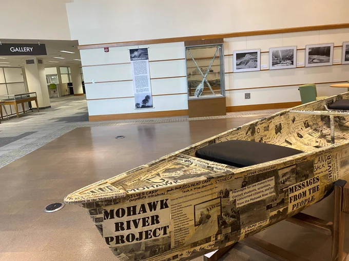 Photo of exhibit with canoe and black and white photographs.