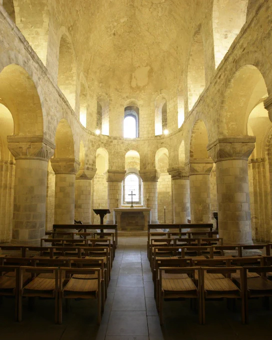 a stone chapel with wooden seats and vaulted ceiling