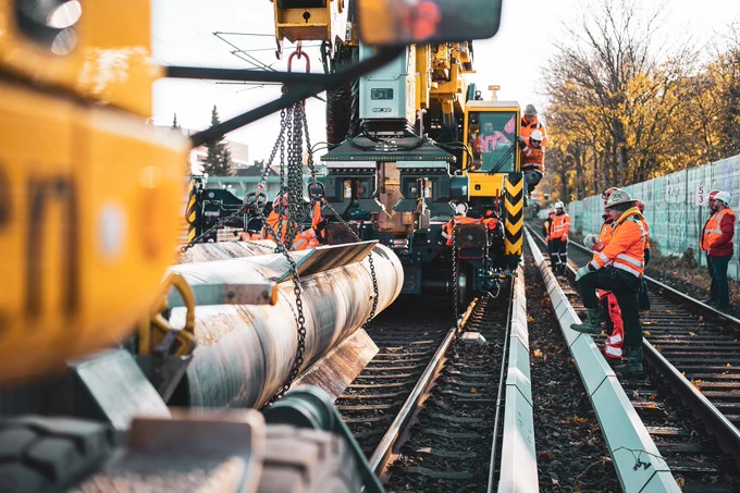 An image of tradespeople and heavy machinery on railroad tracks.
