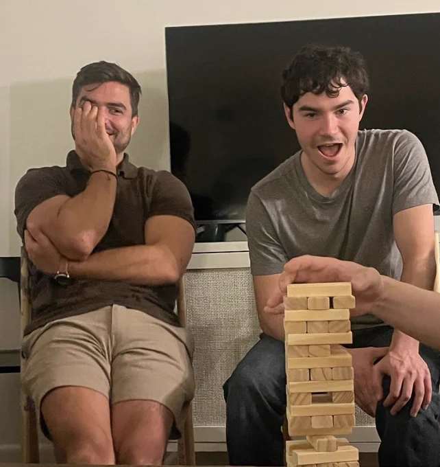 Full-color image of PI Jose Roque sitting with a grad student during a session of Jenga.