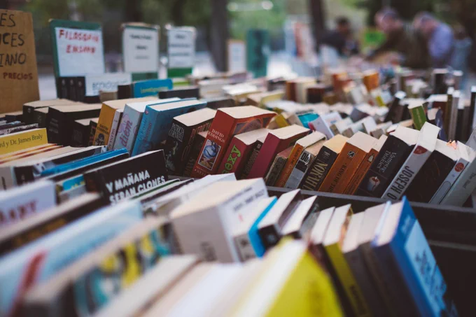 Piles of second-hand books organised into categories. 