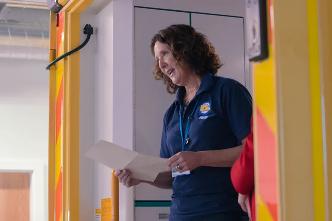 A member of the Embraces team delivers a speech from the back of an ambulance whilst holding a piece of paper