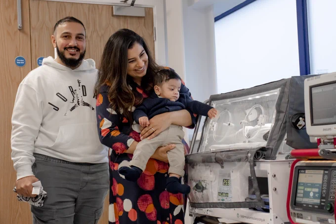 A family smiles alongside a piece of machinery that was used to transport them whilst travelling in a helicopter