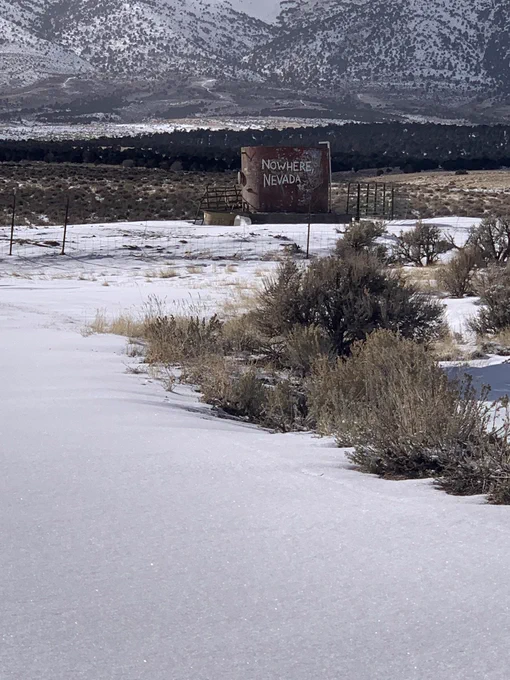 Sign 10-15 mins west of Ely on US 50. The sign reads, “Nowhere, Nevada.” The ground is covered in snow. And the hills in the mountains in the background are also covered in snow.