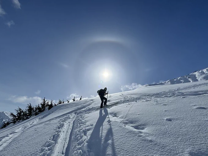 Skier skinning up a snow-covered mountain in the Glacier Ranger District of the Chugach National Forest.
