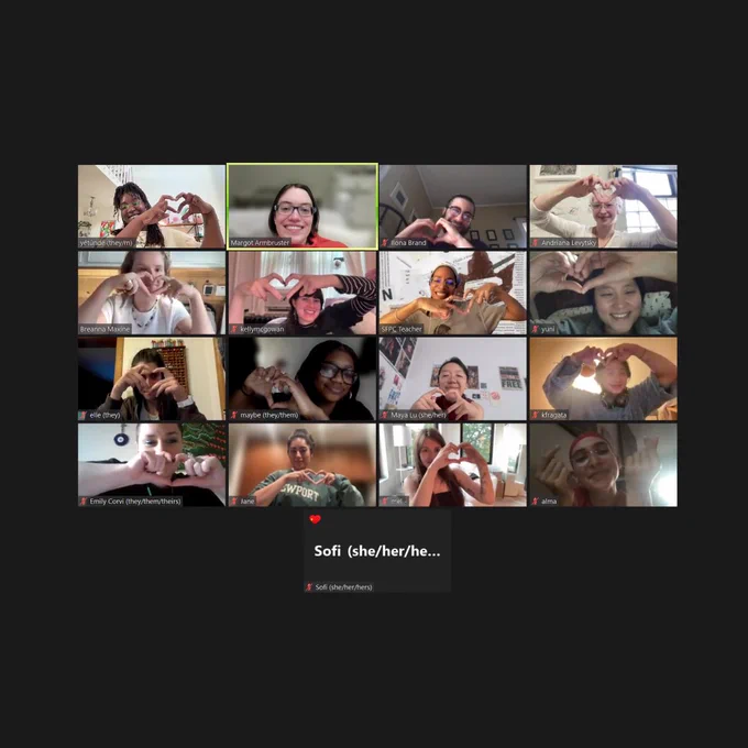 A group of people on a Zoom call smiles and makes heart shapes with their hands.