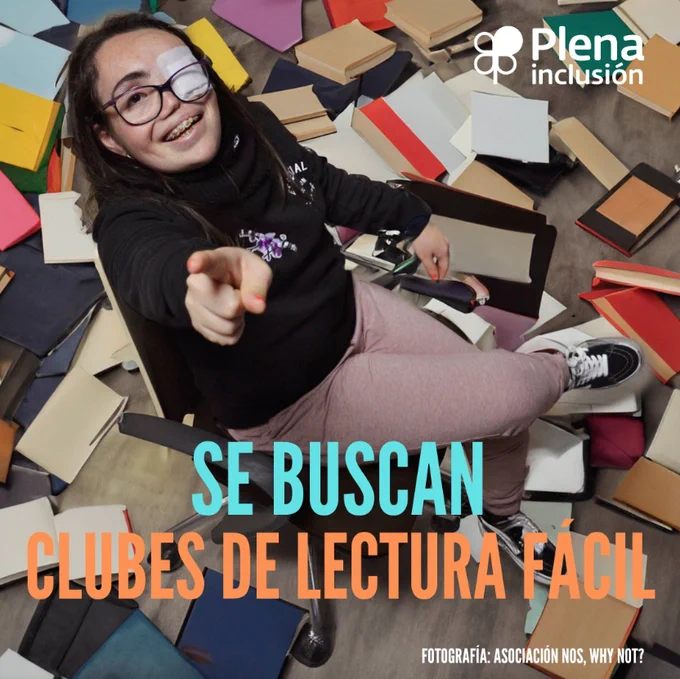 A top view of a seated brunette girl with glasses and one eye covered by a bandage. She points a finger at the camera. Various books are scattered on the floor at her feet.