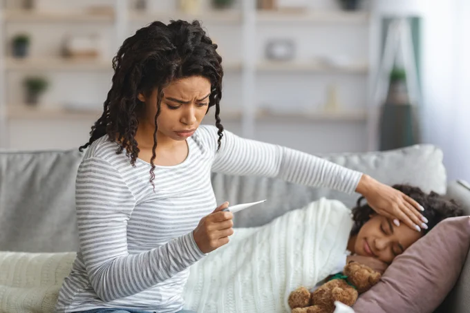 Mother looks concerned as she checks daughter temperature.