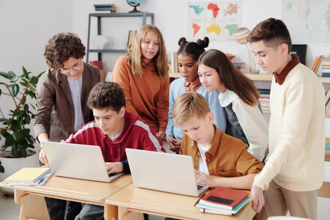 Students gathering behind laptop