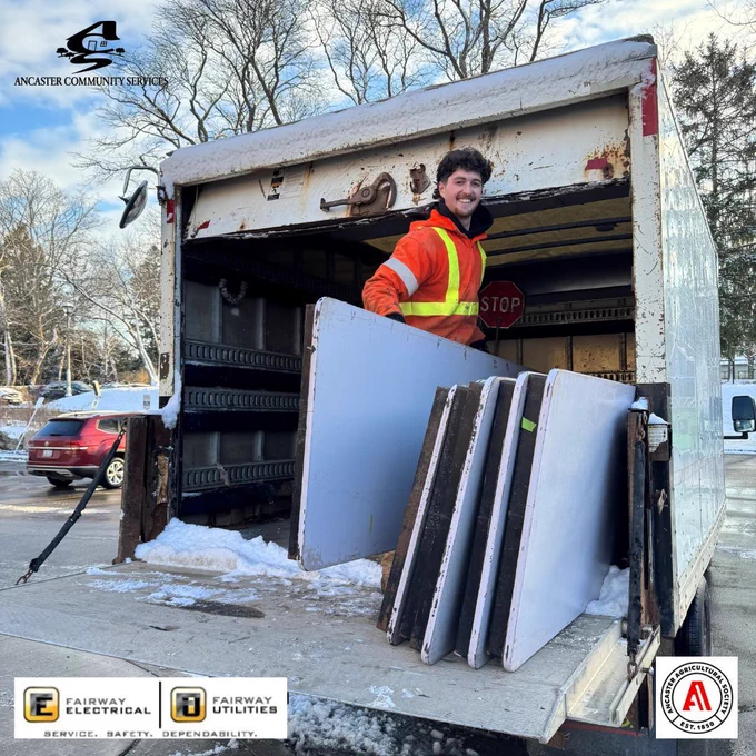 Photo of a young adult loading tables onto a truck. 