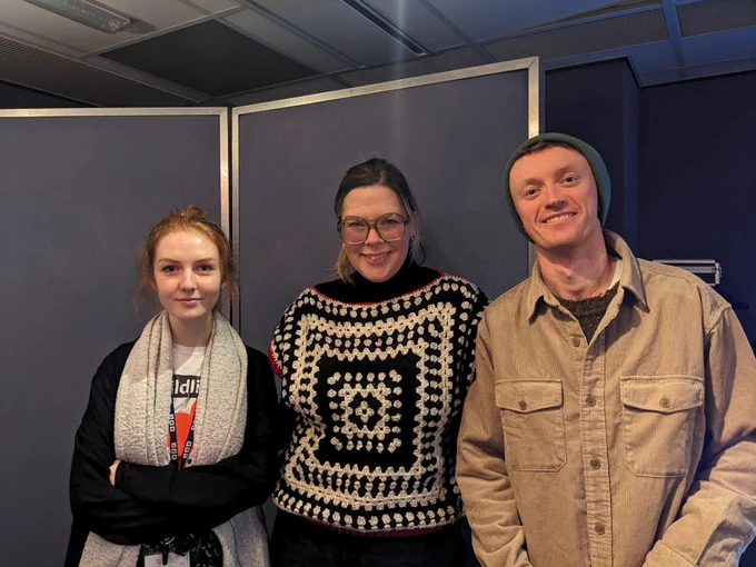 Caitlin in an amazing black and white  crocheted knitwear with Len Pennie in big grey  scarf and Fergus Morgan in a corduroy jacket and blue beanie hat