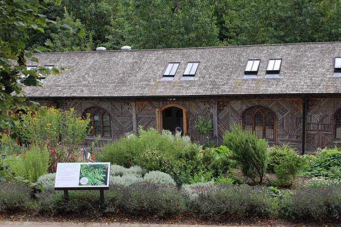 The visitor centre at Pontefract Castle, a long thin building with traditional log patterned frontage. The medieval herb garden is in front of the building