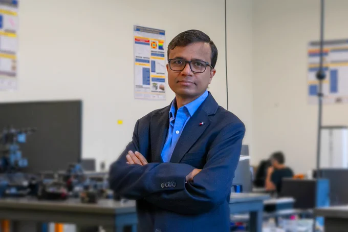 A person in a navy blazer standing in an engineering lab.