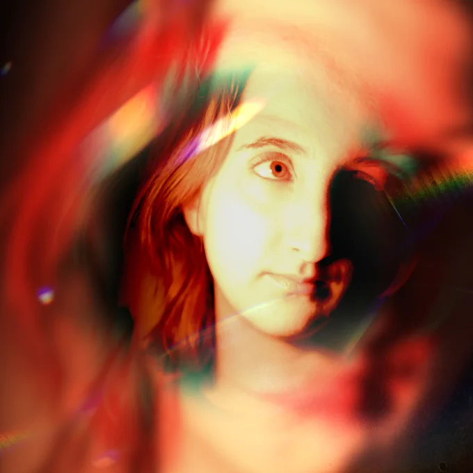 A close-up portrait of a young person illuminated by vibrant red and orange tones, with prismatic light streaks adding a surreal and ethereal quality to the image.