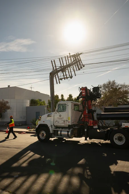 A truck is parked in front of a power pole damaged in the windstorm.
