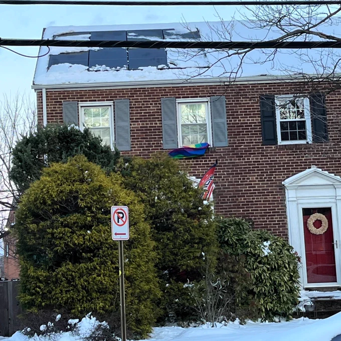 Snow melting off solar panels on top of a brick home.