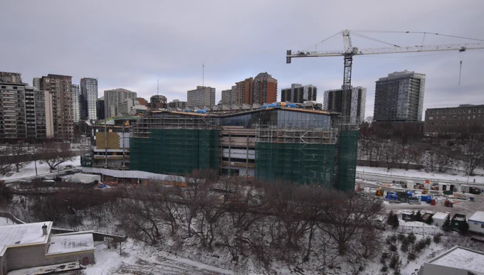 Photo de l'extérieur du bâtiment montrant les fenêtres et le côté du bâtiment, avec quelques échafaudages au premier plan.