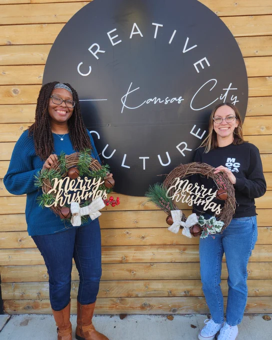 MOCSA HR Team at Creative Culture in Westport Kansas City MO holding two wooden wreaths that say Merry Christmas.