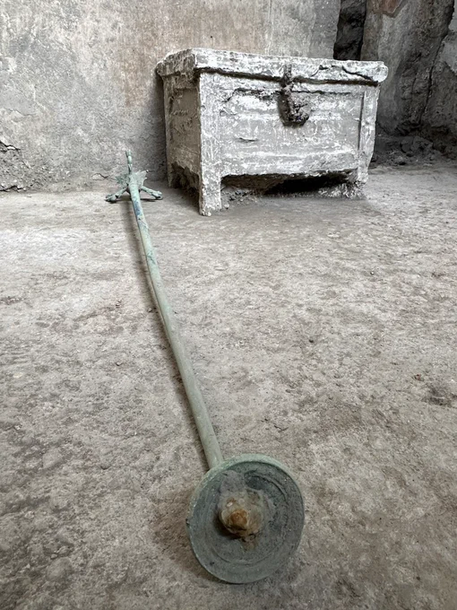 Bronze lamp stand lying on the floor and a plaster cast of a wooden chest in the background