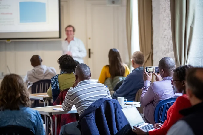 A room of people listening to a presenter. 