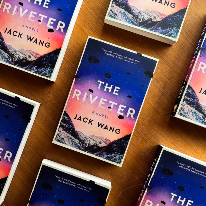 A photo of copies of The Riveter side-by-side on a wooden table. The photo is taken from above. 
