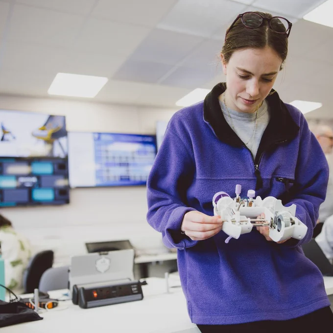 Photo of researcher holding open robot in the lab.